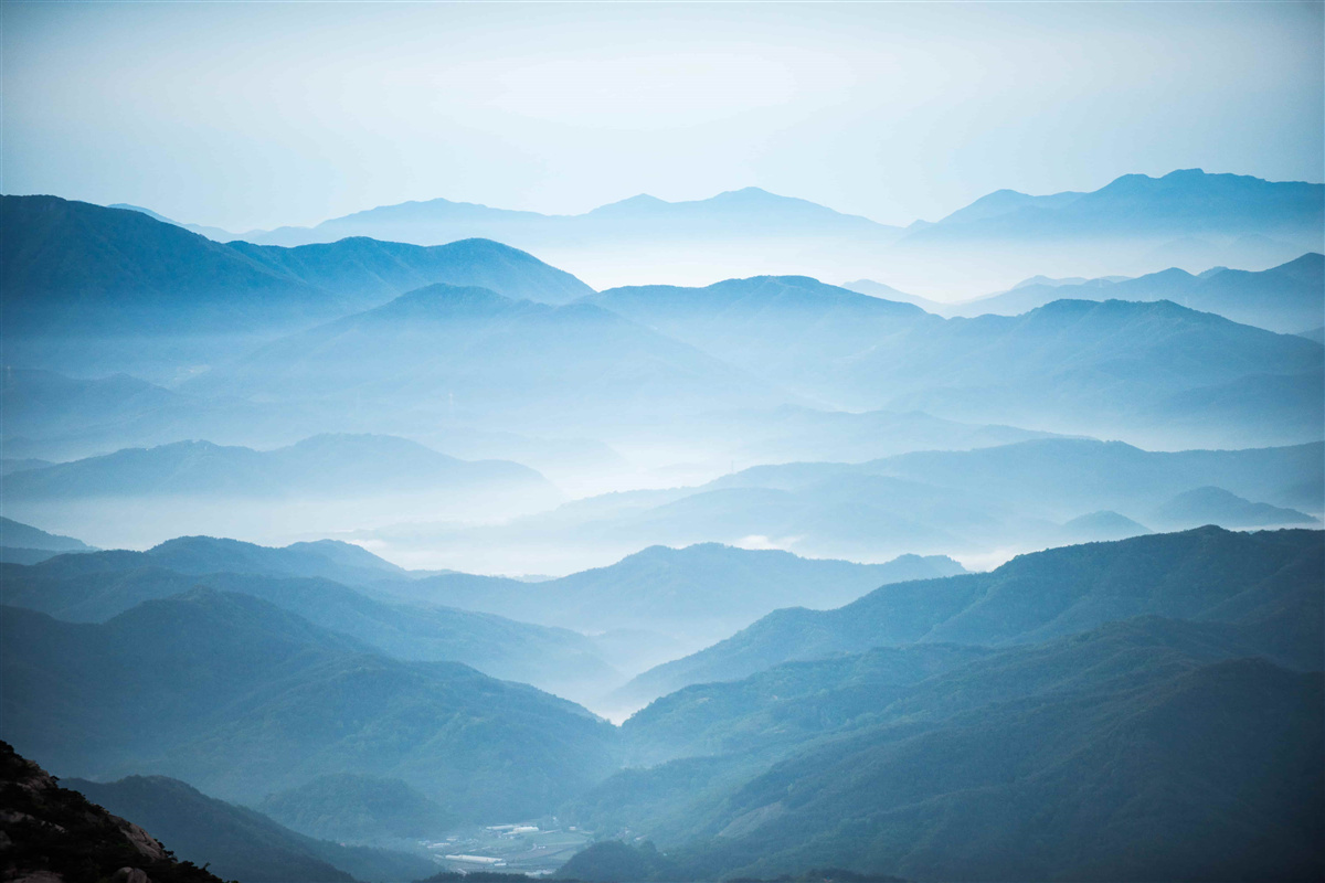 Fototapeten Morgennebel umhüllt die Oberteile der Berge