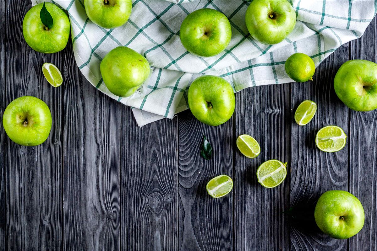 Fototapeten Lime und grüne Äpfel liegen auf dem Tisch