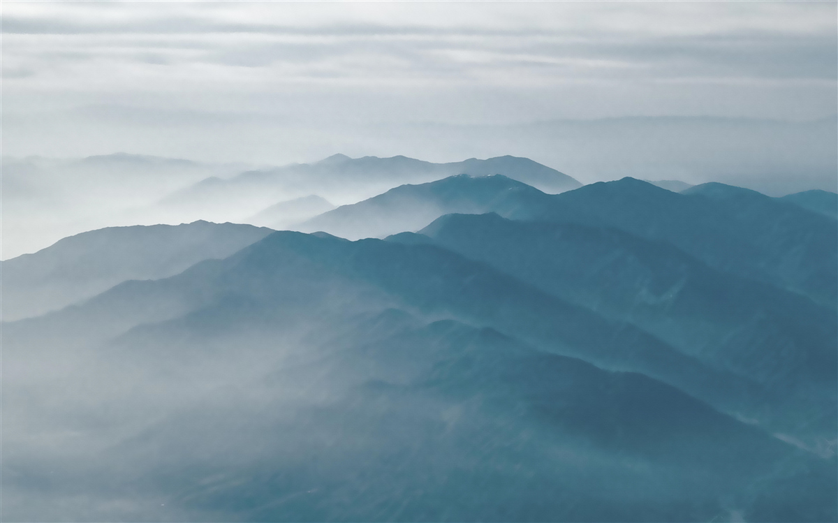 Fototapeten Morgennebel umhüllt die Oberteile der Berge