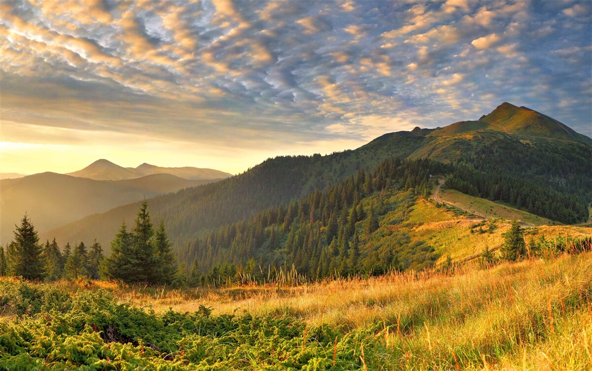 Fototapeten Die Wolken über den Bergen sind in den warmen Farben des Sonnenuntergangs gestrichen
