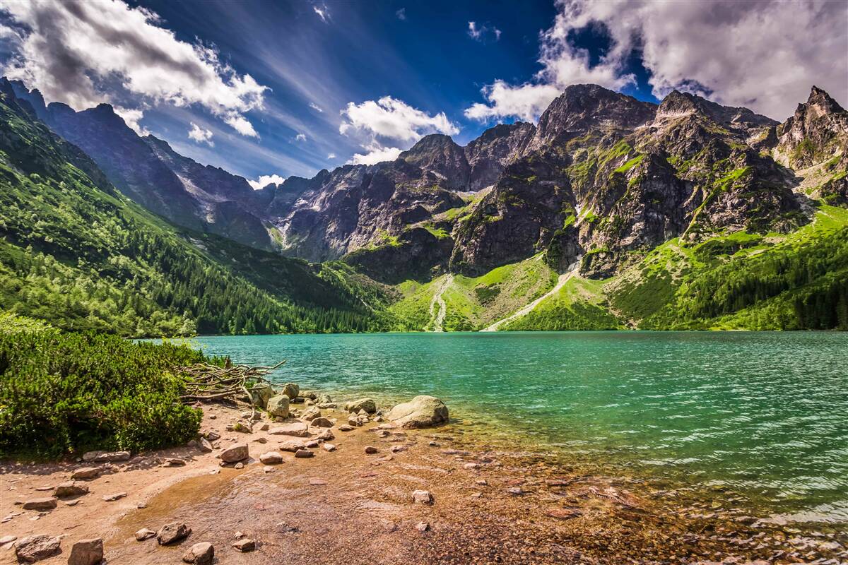 Fototapeten Sommertag in der Nähe des Sees, umgeben von grünlichen Bergen