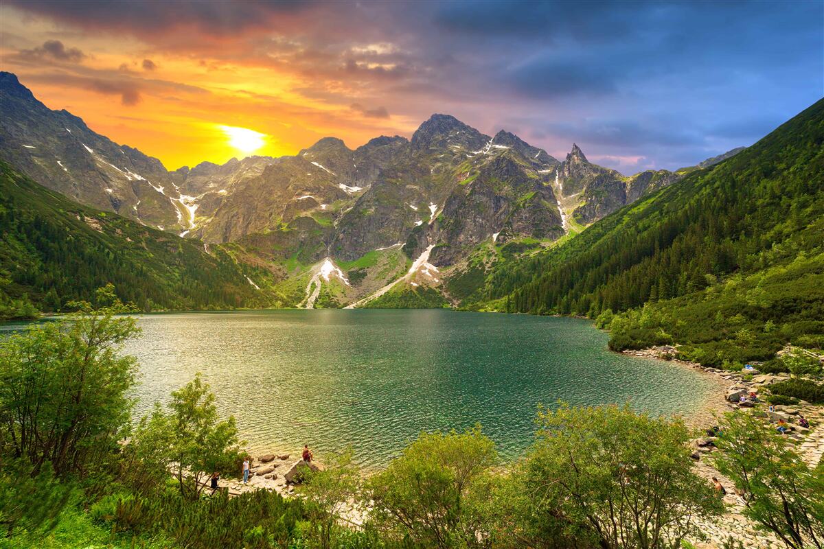 Fototapeten Ein spektakulärer Sonnenuntergang hinter den Bergketten in der Nähe des Sees
