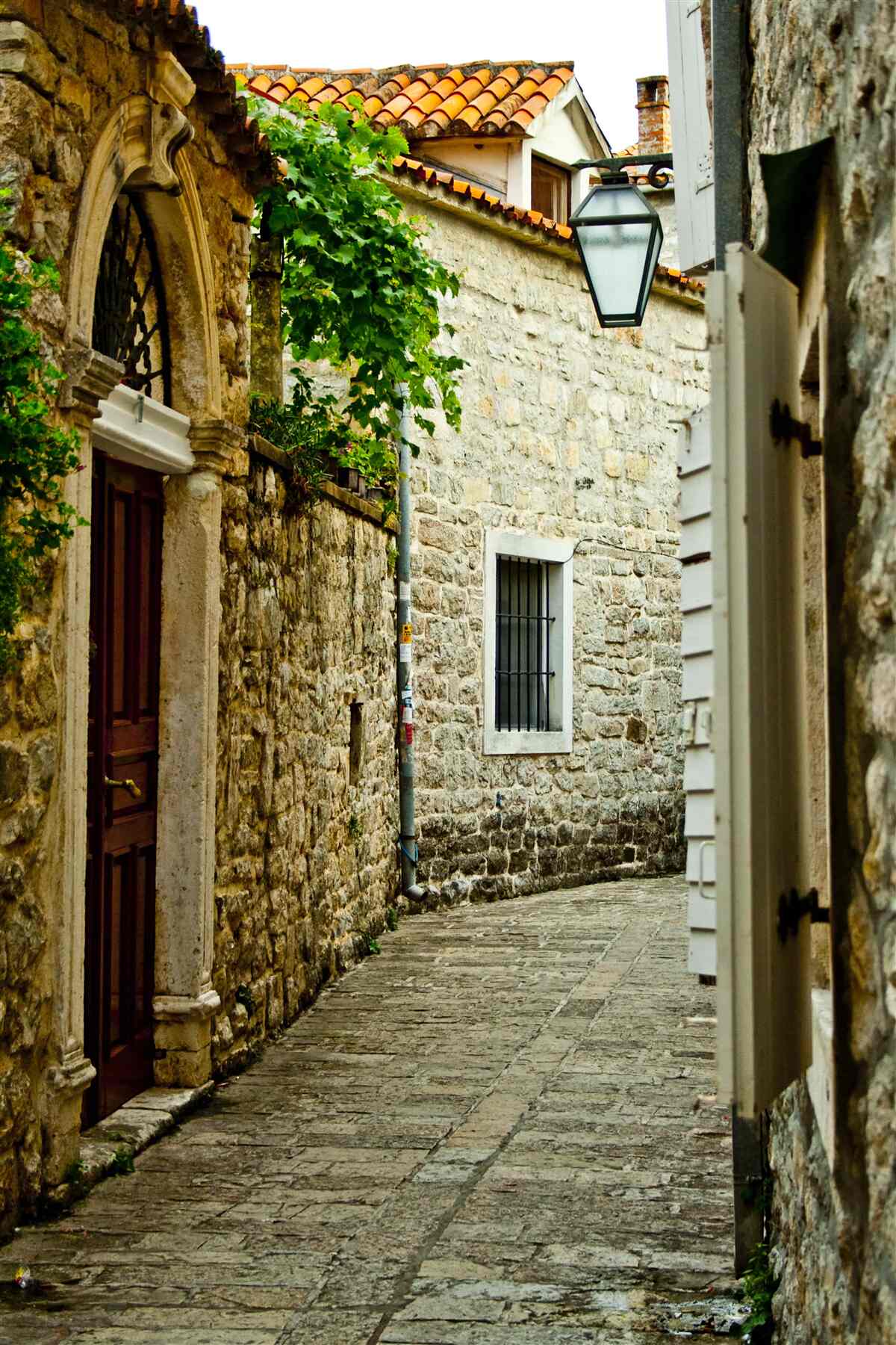 Fototapeten Im Sommer säumte eine alte Straße mit einem Stein
