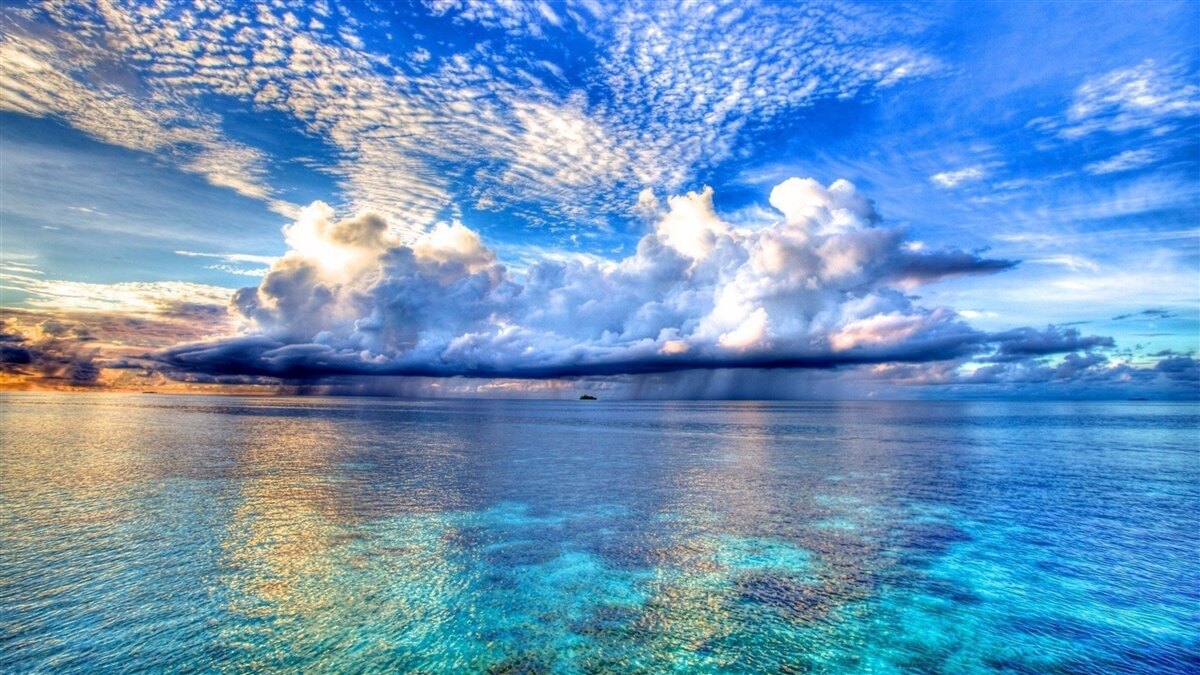 Fototapeten Die Wolken schweben sanft über der blauen Wasseroberfläche des Wassers