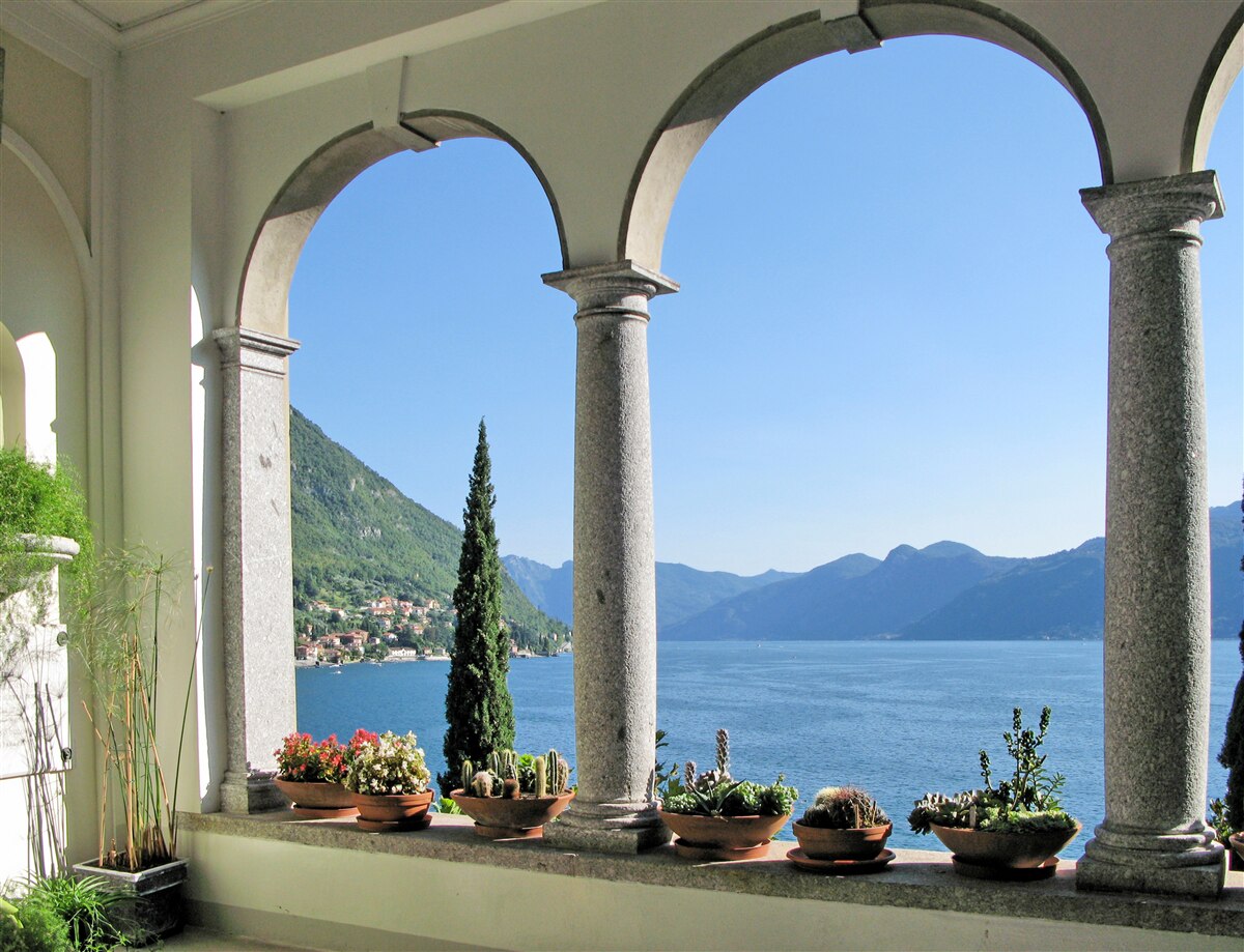 Fototapeten Balkon mit gewölbten Löchern und Blick auf Wasser und Berge