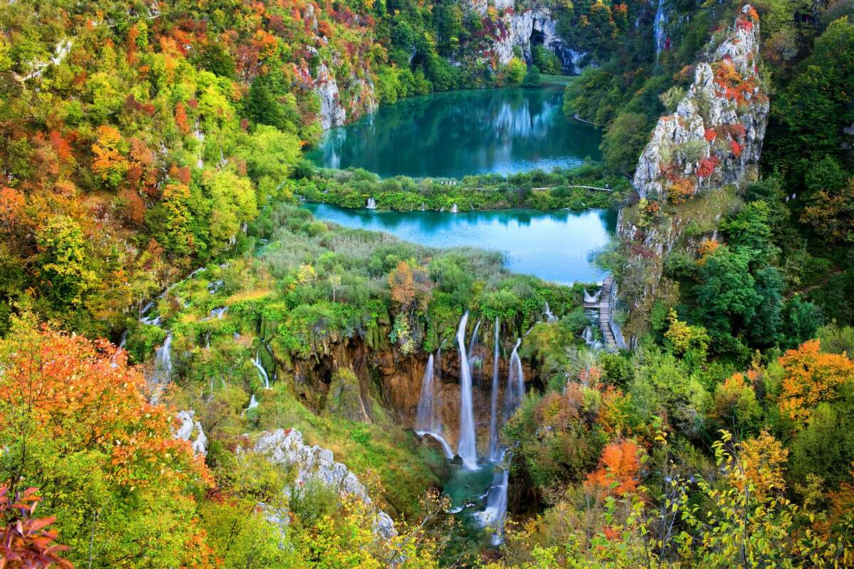 Fototapeten Herbstwald mit einem fließenden Wasserfall dekoriert