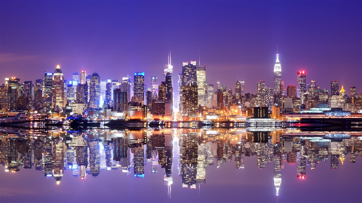Fototapeten Eine große Stadt, die von hellen Lichtern vor dem Hintergrund der untergehenden Sonne beleuchtet wurde